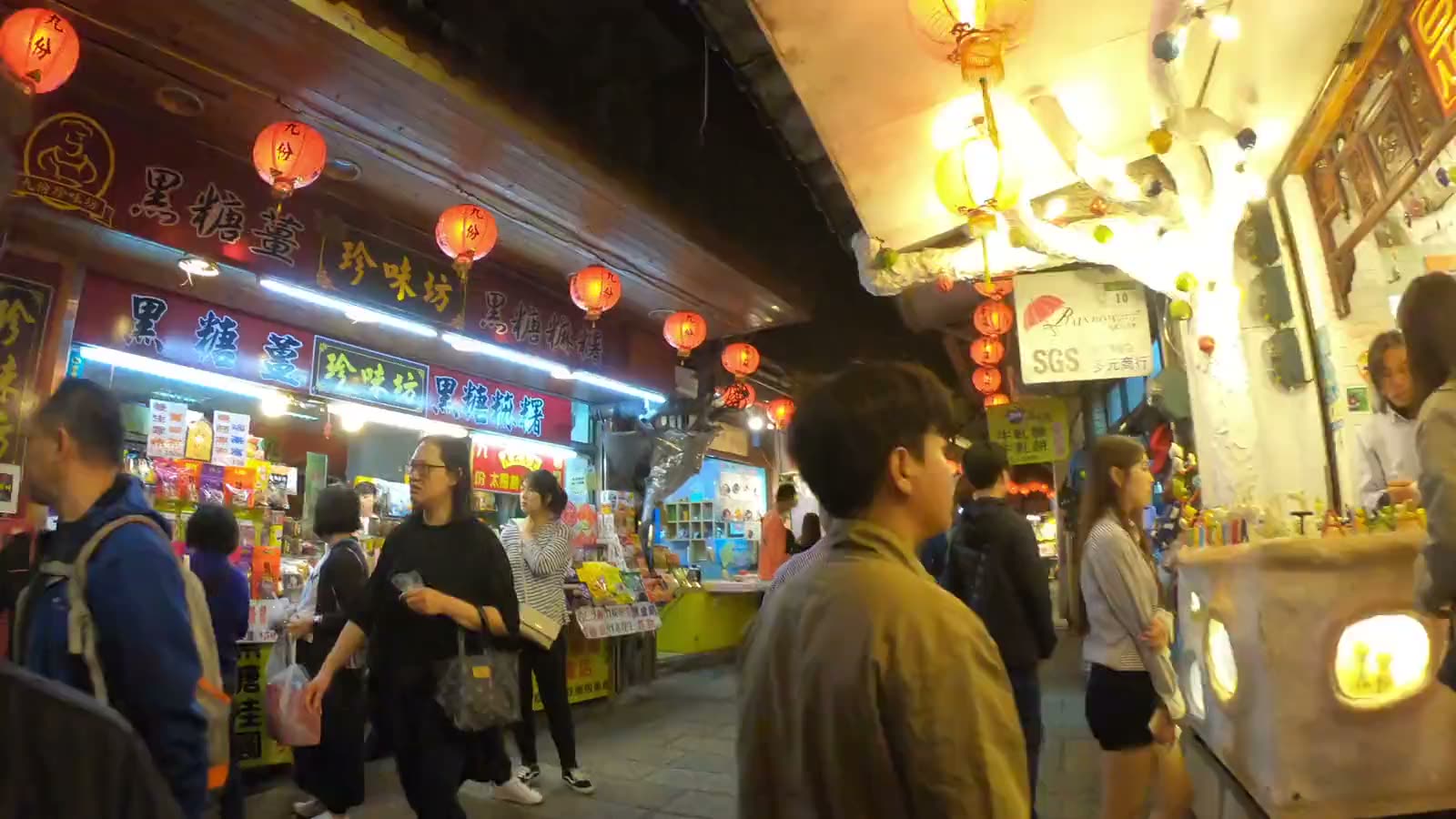 A bustling night market at dusk, lit by signs and lanterns